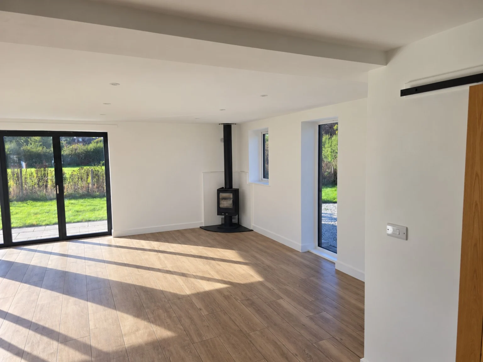White interior walls and ceiling with timber flooring and a wood-burning stove